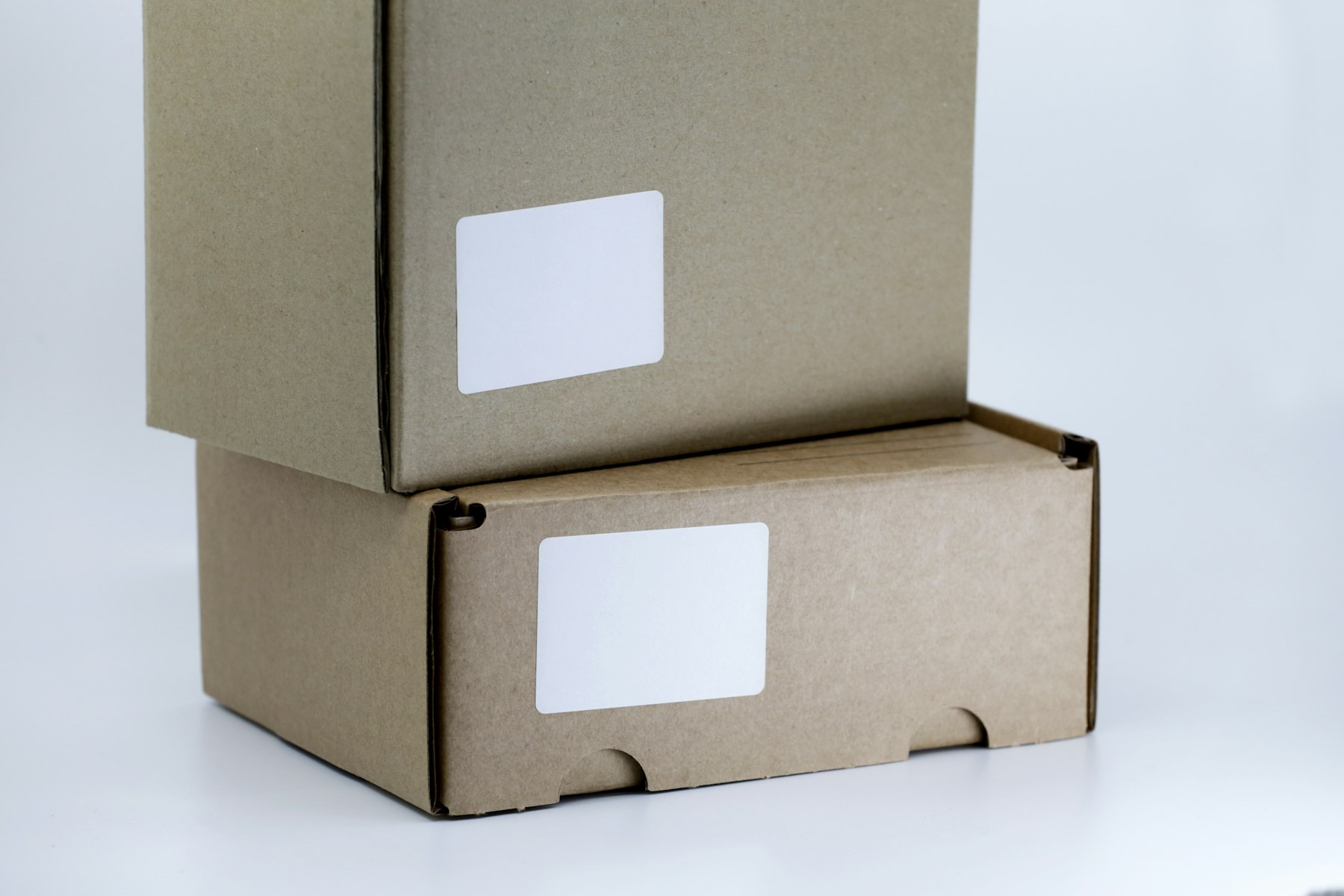 Two plain cardboard shipping boxes stacked on a white table
