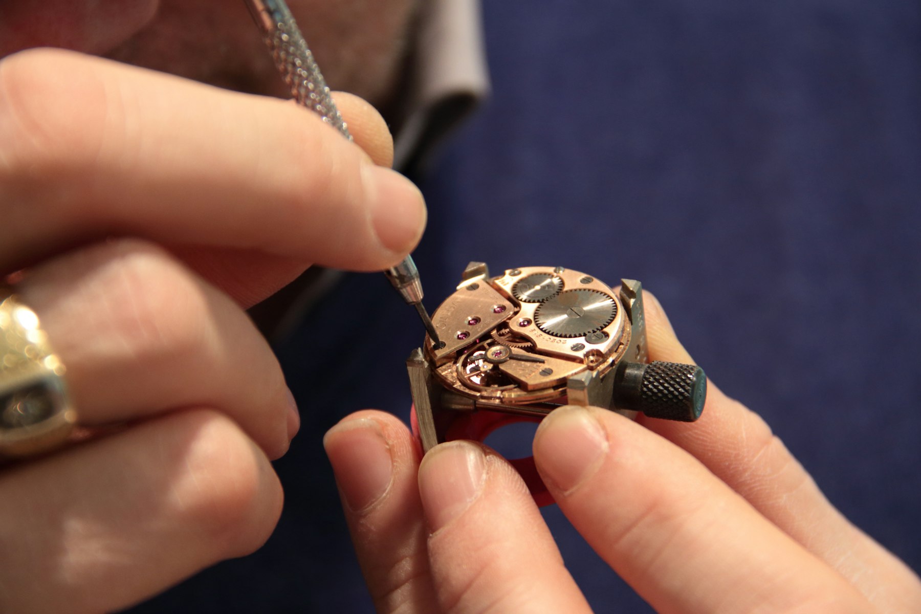 A watchmaker's fingers working on a small mechanical movement with a fine tool